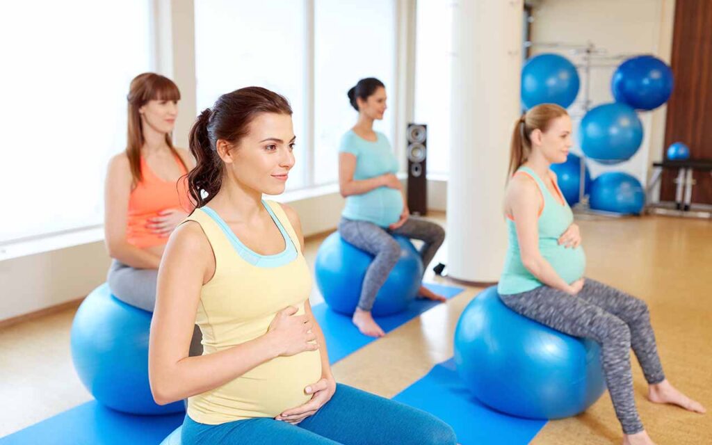 Fertility Prenatal and Postpartum Wellness - happy pregnant women sitting on exercise balls in gym
