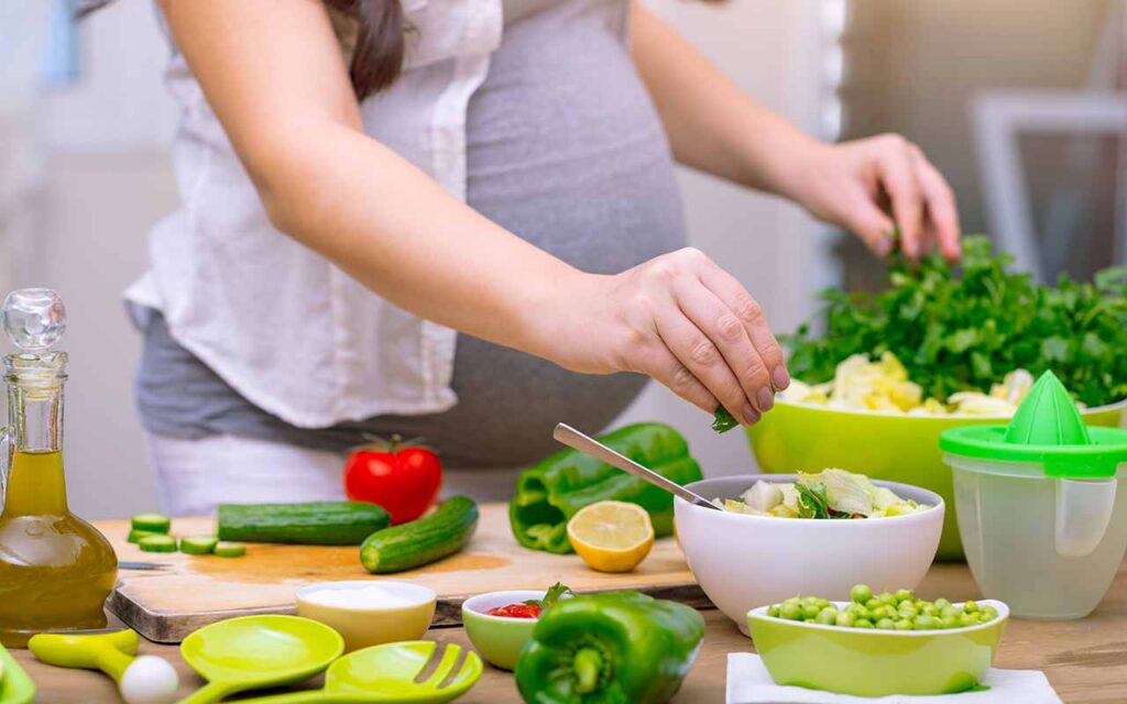 Fertility Prenatal and Postpartum Wellness - Happy Pregnant Woman Cooking At Home